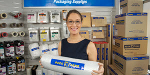 woman holding bubble wrap in a room full packaging supplies